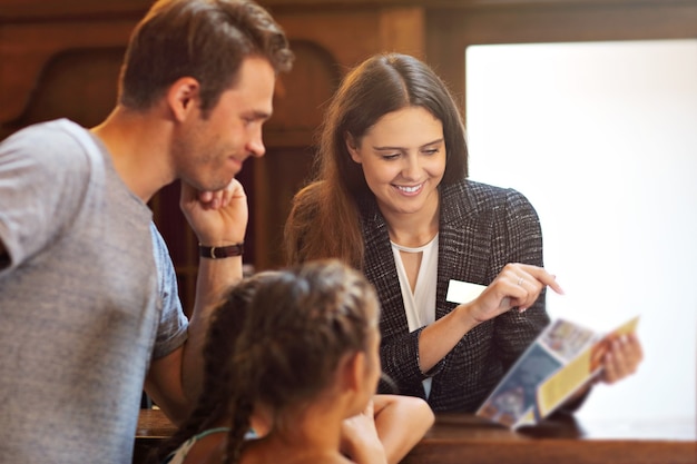 Familia feliz que se registra en el hotel en la recepción