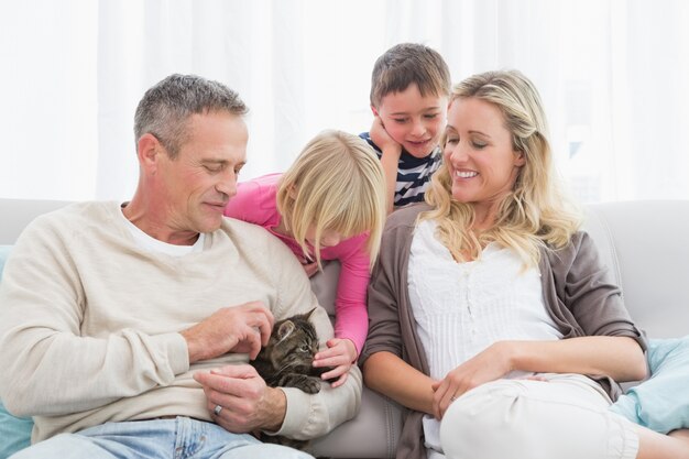 Familia feliz que se sienta con el gatito del animal doméstico junto