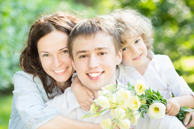 Familia feliz con ramo de flores de primavera contra el fondo verde borroso