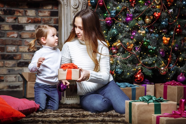 Familia feliz con regalos de Navidad cerca del árbol de Navidad