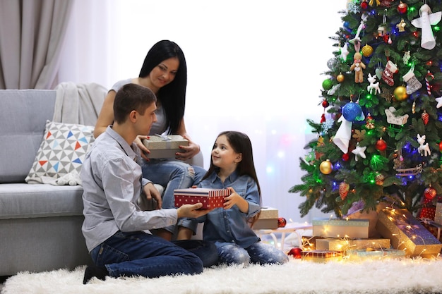 Familia feliz con regalos en la sala de Navidad decorada