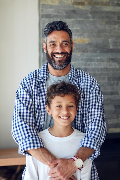 Familia feliz y retrato de abrazo con el niño y el padre juntos con sonrisa y unión en un nuevo hogar Apoye al papá y al niño con solidaridad juvenil y salón con hombre orgulloso y cuidado en la casa con amor