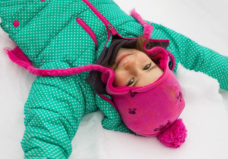 Foto família feliz - retrato de uma menina deitada na neve e rindo no dia de inverno