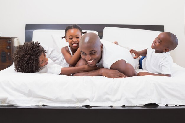 Familia feliz riendo juntos en la cama