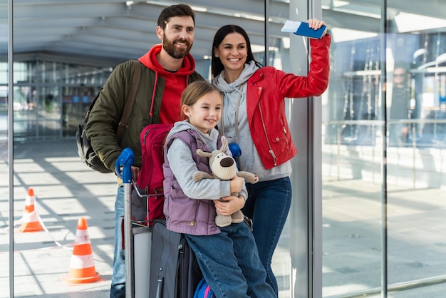 Familia feliz en las salidas del aeropuerto. Personas en la terminal preparándose para las vacaciones mientras miran a la distancia con caras felices