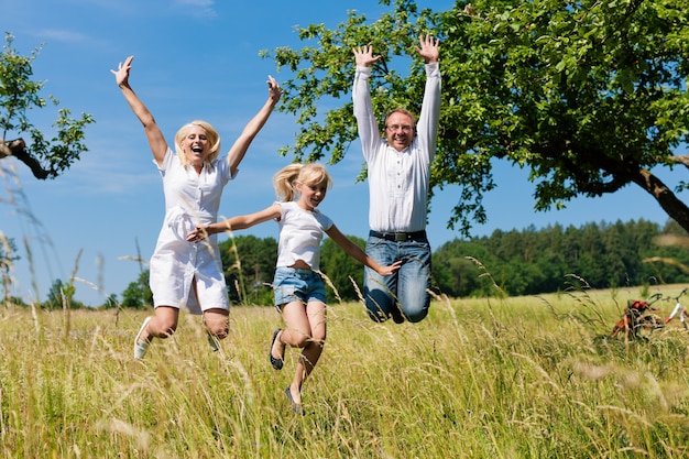 Familia feliz saltando al aire libre en el sol