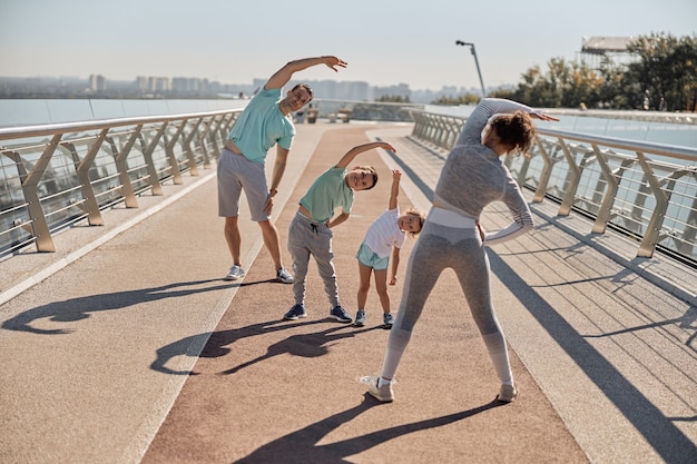 Família feliz, saudável e esportiva fazendo treinos em um dia ensolarado