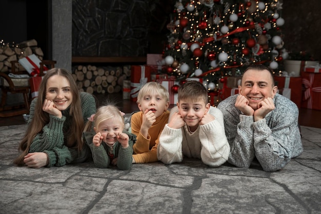 Família feliz se diverte perto da árvore de Natal Pai mãe e três filhos em casa feriado de Natal