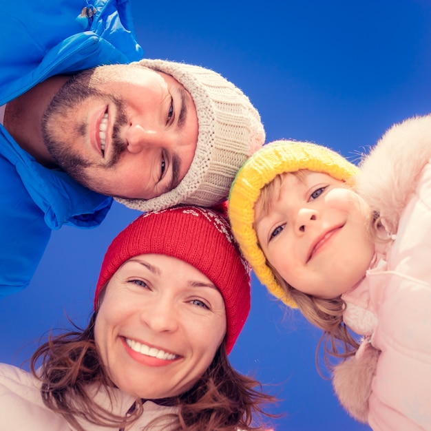 Família feliz se divertindo ao ar livre no inverno contra o fundo do céu azul