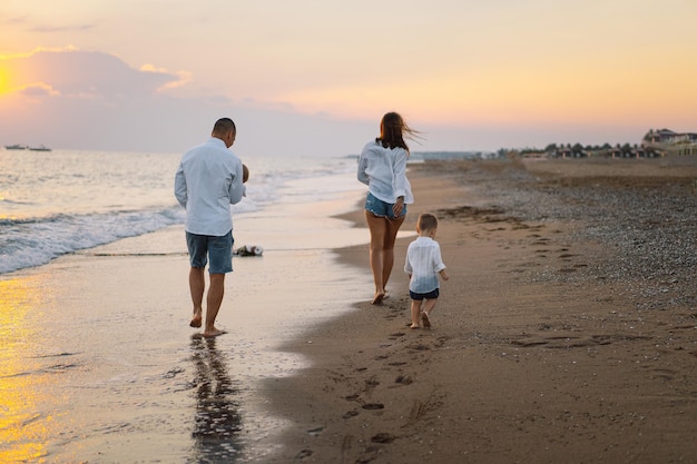 Família feliz se divertindo jogando praia nas férias de verão na praia Conceito de família e férias feliz Seascape ao pôr do sol com lindo céu Família na praia