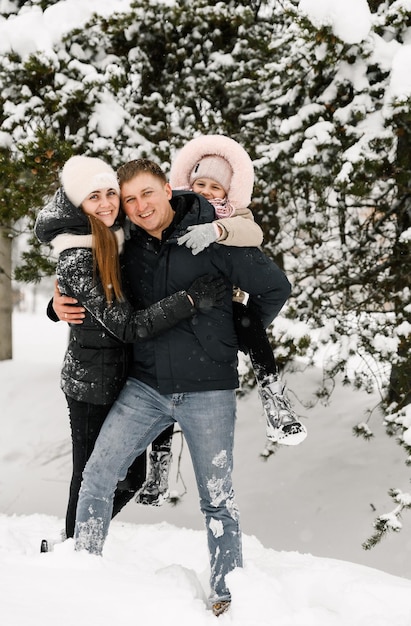 Família feliz se divertir na floresta de inverno. Mãe, pai e filha brincando com neve. Conceito de família. Gostando de passar o tempo juntos