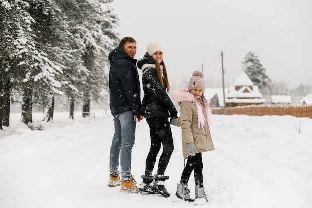 Família feliz se divertir na floresta de inverno. Mãe, pai e filha brincando com neve. Gostando de passar algum tempo juntos. Conceito de familia