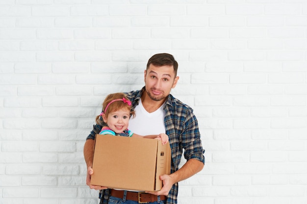 Família feliz se muda para um novo apartamento pai e filha brincando e se diverte em pacotes em caixas de papelão