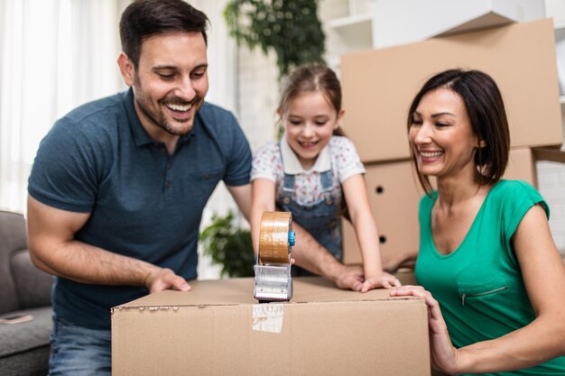 Família feliz se mudando para sua nova casa e desempacotando caixas de papelão.