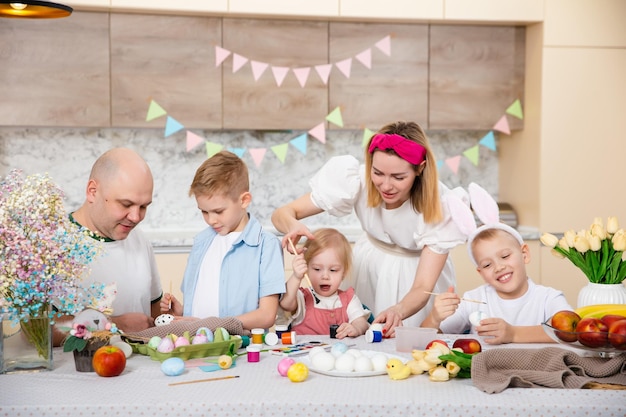 Família feliz se preparando para a Páscoa Crianças bonitas pintando ovos Atividade doméstica Conceito de unidade e amor Mãe pai filho filha Irmãos e irmãs