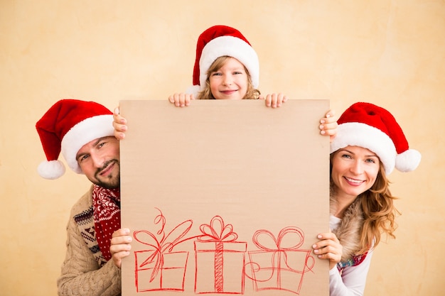 Família feliz segurando cartaz de Natal em branco. Conceito de férias de natal