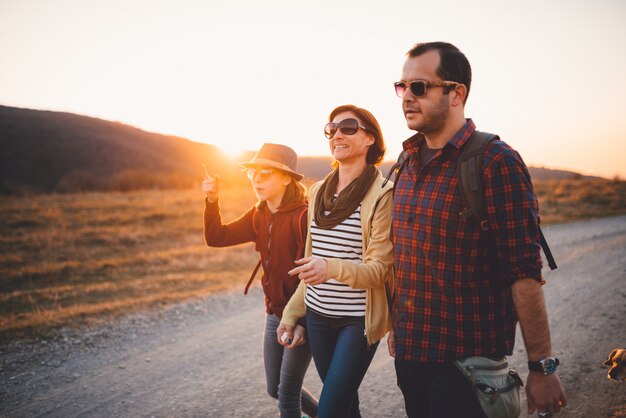 Familia feliz senderismo en un camino de tierra durante el atardecer