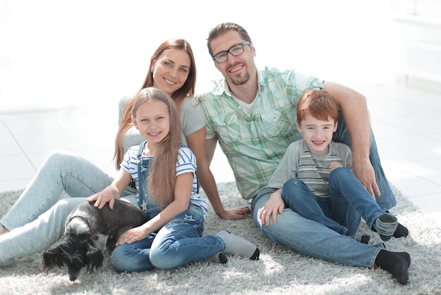 Familia feliz sentada en la alfombra en un apartamento nuevo