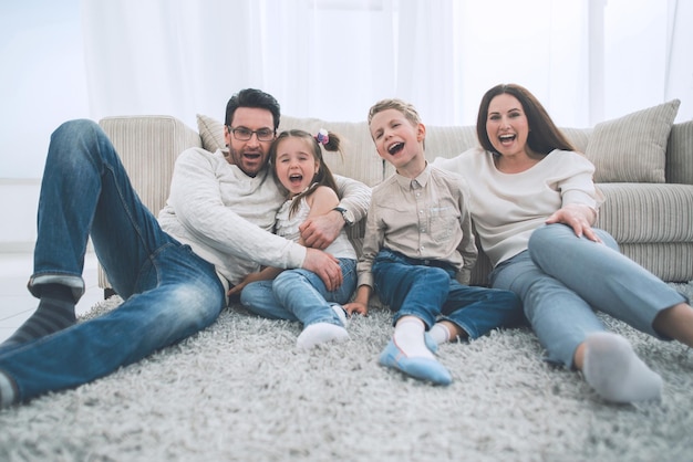 Familia feliz sentada en la alfombra en la sala de estar foto con espacio para copiar