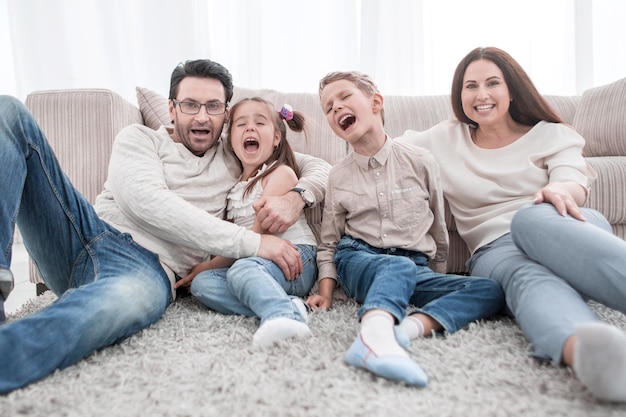 Familia feliz sentada en la alfombra en la sala de estar