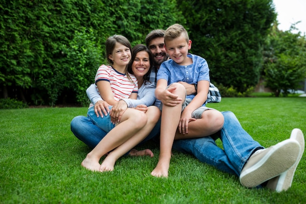 Foto familia feliz sentada en el césped en el parque en un día soleado