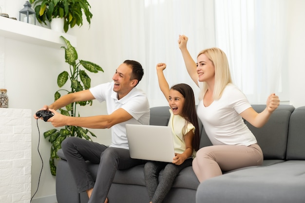 Família feliz sentada em um sofá e jogando videogame.