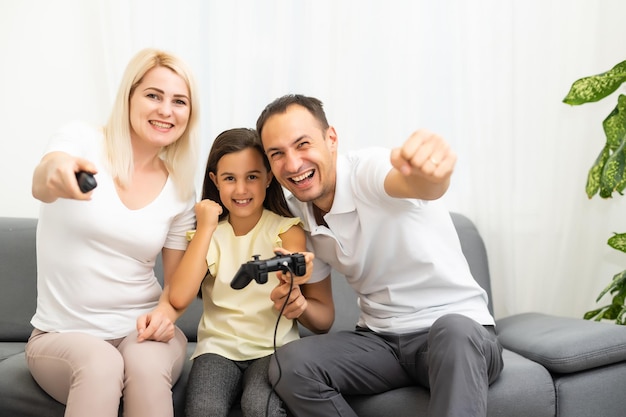 Família feliz sentada em um sofá e jogando videogame.