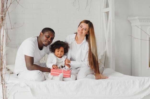 Família feliz sentada em uma cama branca