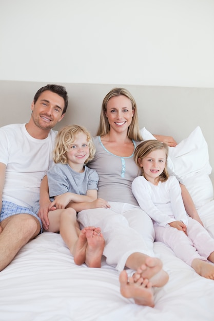 Família feliz sentada na cama