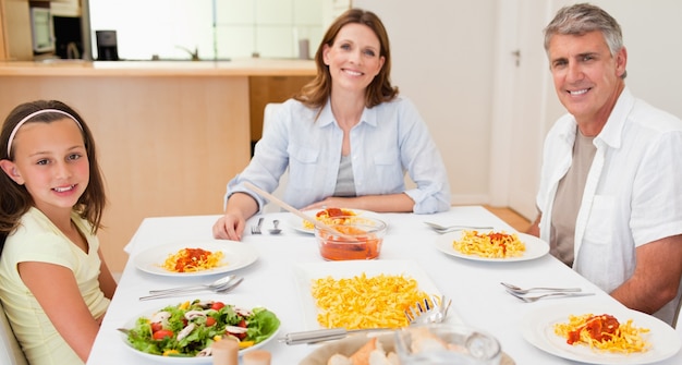 Família feliz sentada na mesa de jantar