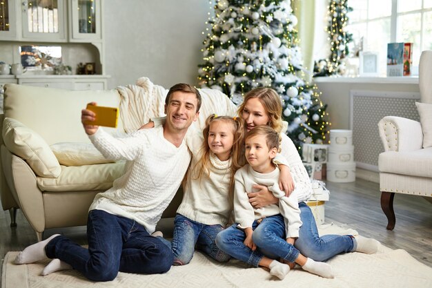 Família feliz sentada na sala de estar tirando uma selfie com o smartphone