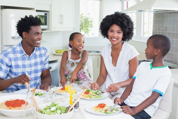 Família feliz sentada para jantar juntos