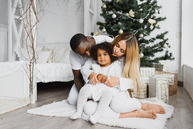 Família feliz sentada perto da árvore de natal