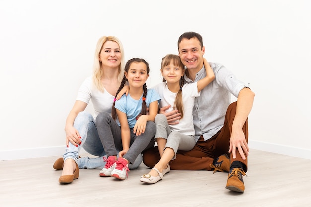 Familia feliz sentada en un piso de madera. Padre, madre e hijo se divierten juntos. Día de la mudanza, nuevo concepto de hogar