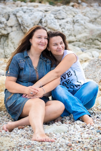 Familia feliz sentada sobre las piedras frente al mar en verano.