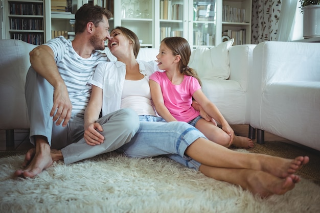 Família feliz sentado no tapete na sala de estar