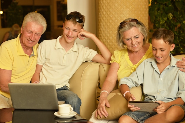 Familia feliz sentado con ordenador portátil y tableta en la mesa