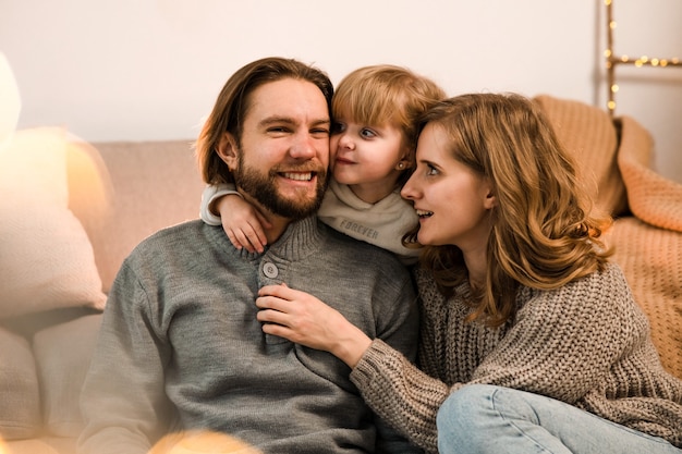 Familia feliz sentado en el sofá en la acogedora habitación decorada de Navidad