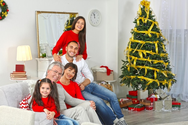 Familia feliz sentado en el sofá en el salón decorado para Navidad