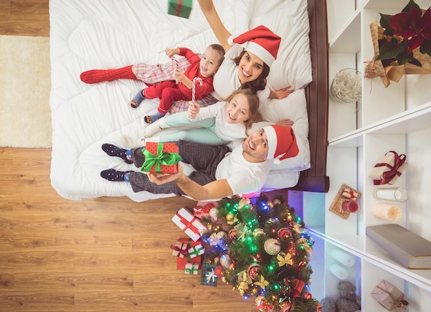 La familia feliz se sienta en una cama con regalos. vista desde arriba