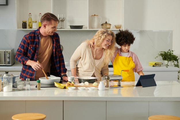 Familia feliz siguiendo la receta en tableta