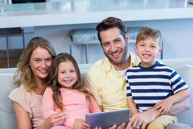 Familia feliz en el sofá junto con tableta