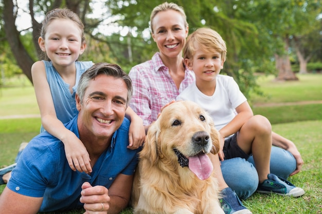 Familia feliz sonriendo a la cámara con su perro