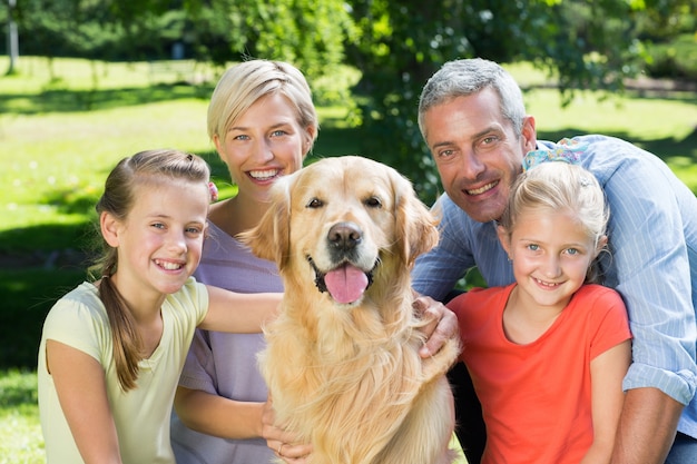 Familia feliz sonriendo a la cámara con su perro