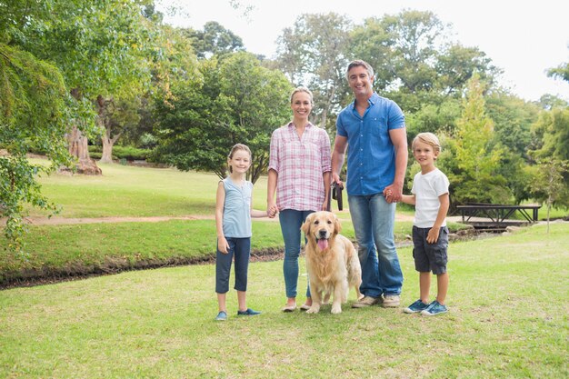 Familia feliz sonriendo a la cámara con su perro