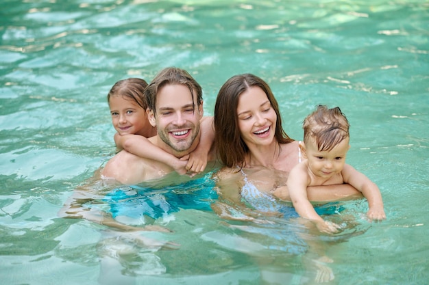 Familia feliz sonriente nadando en una piscina