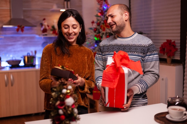 Familia feliz sorprendiéndose unos a otros con regalo de Navidad con cinta