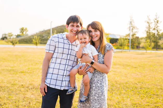 Família feliz, sorrindo para a câmera em um dia ensolarado.