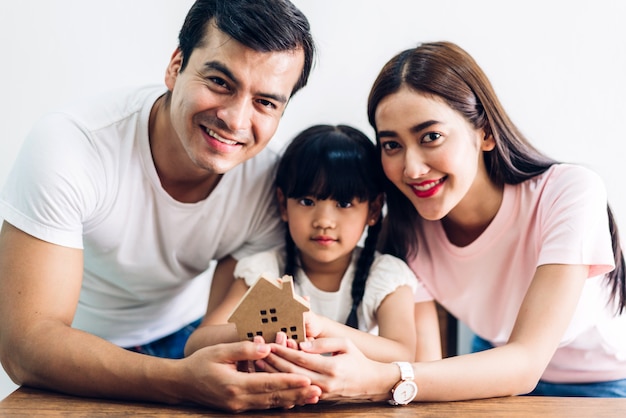 Familia feliz sosteniendo una casa de papel en manos