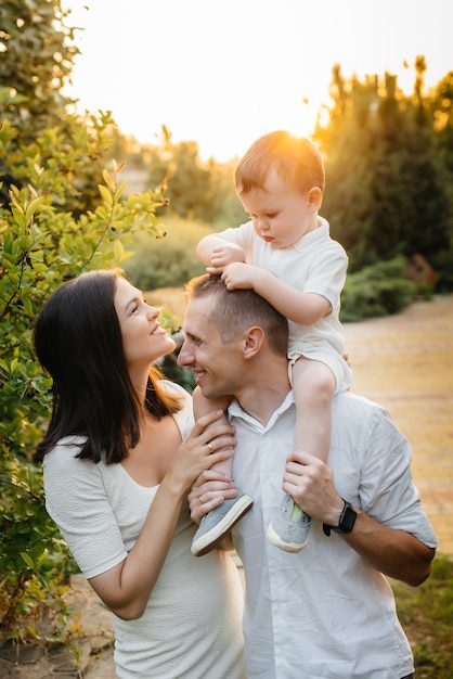 Familia feliz con su hijo caminando en el parque al atardecer. Felicidad. Amor